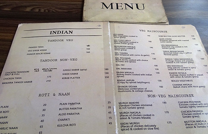 Restaurant menu showing various Indian dishes, possibly indicating a bad restaurant with worn-out menus.