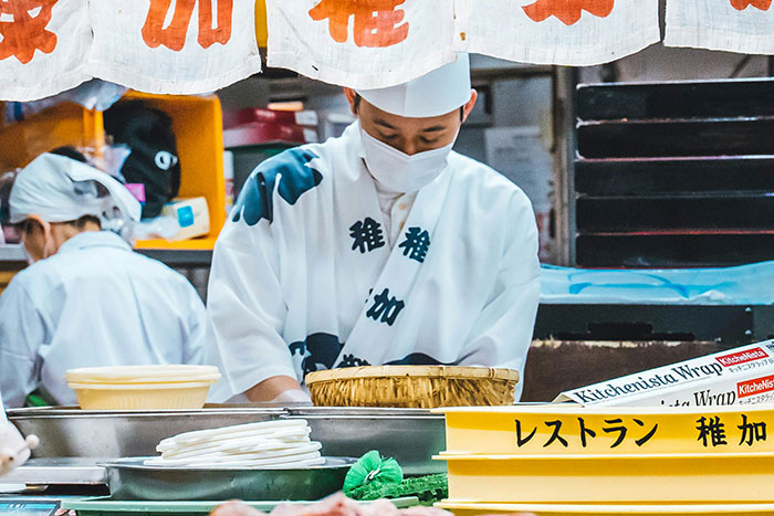 Chef in a traditional outfit prepares food in a restaurant kitchen, highlighting potential signs of a bad restaurant experience.