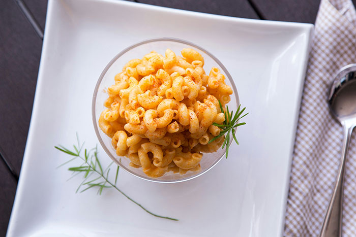 Macaroni and cheese in a glass bowl on a white plate, garnished with herbs, indicating a bad restaurant experience.