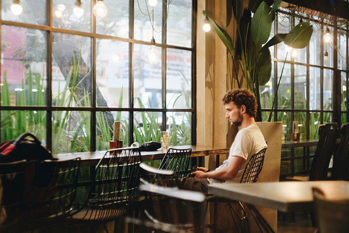 Man sitting alone in a poorly lit restaurant, highlighting a potential sign of being in a bad restaurant.