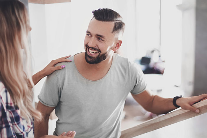 Man with a beard smiling and chatting with a woman, discussing surprising things about men.