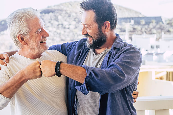 Two men happily fist-bumping outdoors, illustrating surprising things to know about men.