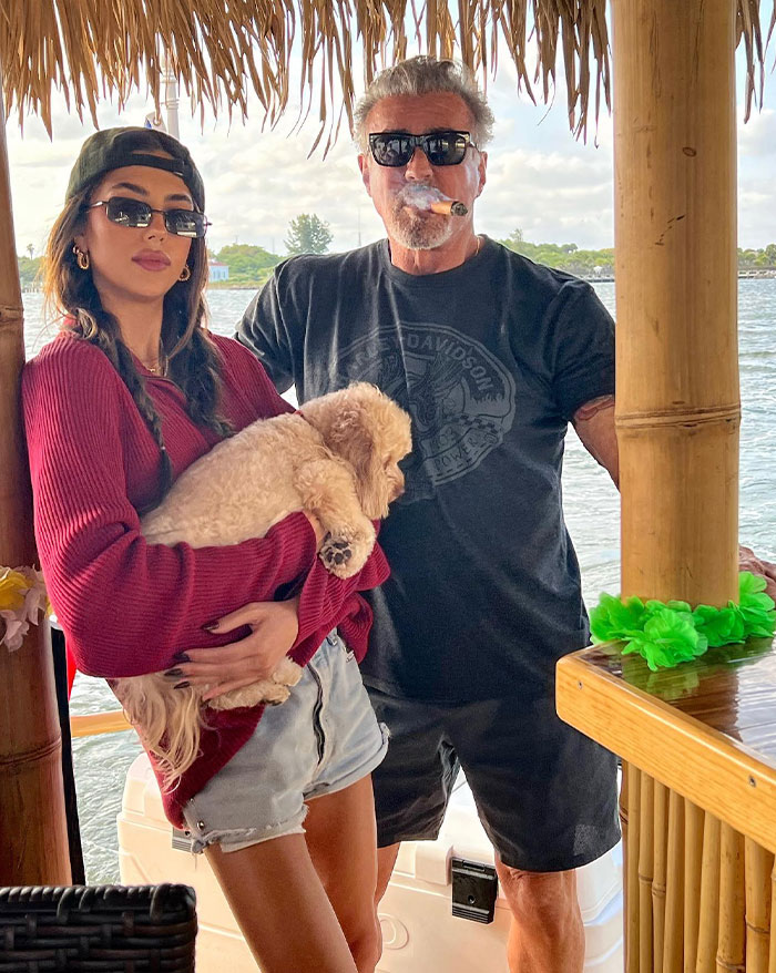 Sylvester Stallone with cigar and Sistine Rose Stallone holding a dog on a boat, related to Sylvester Stallone&rsquo;s children.