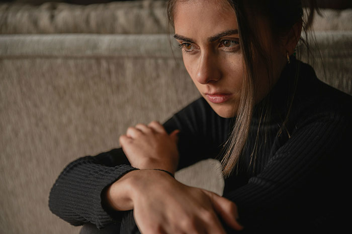 Teen looking thoughtful, sitting on a couch, prioritizing her future over babysitting her sister's kids.