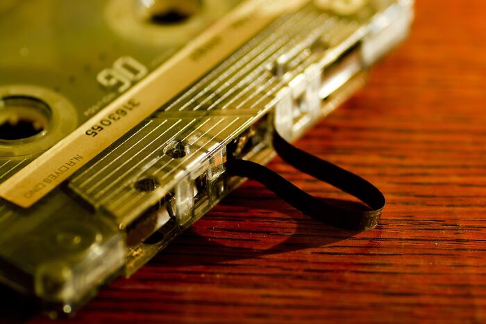 Close-up of a vintage cassette tape with its ribbon partially unraveled on a wooden surface, symbolizing Unpopular Opinion Poll.