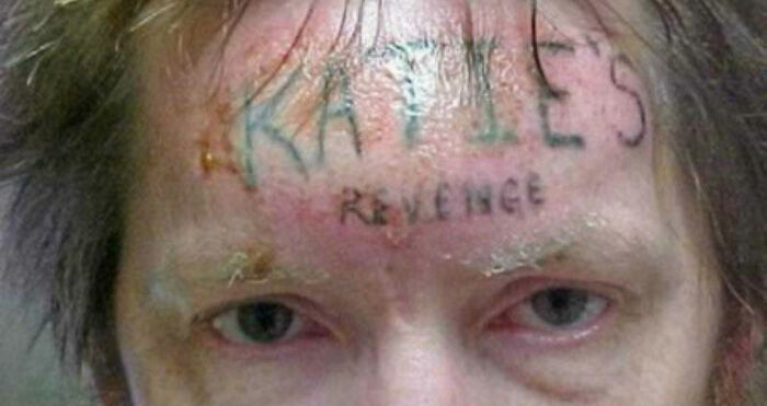 Person with "Katie's Revenge" tattooed on forehead, showcasing one of the worst tattoos given by tattoo artists.