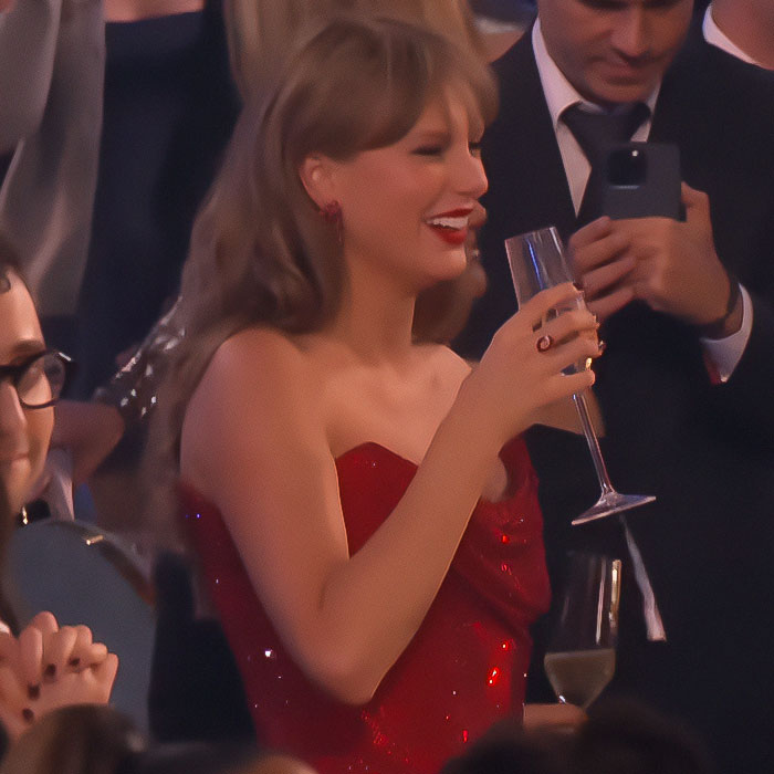 Woman in a red dress holding a champagne glass at an event.