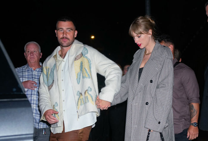 Taylor Swift and Travis Kelce holding hands, sparking fan discussions.