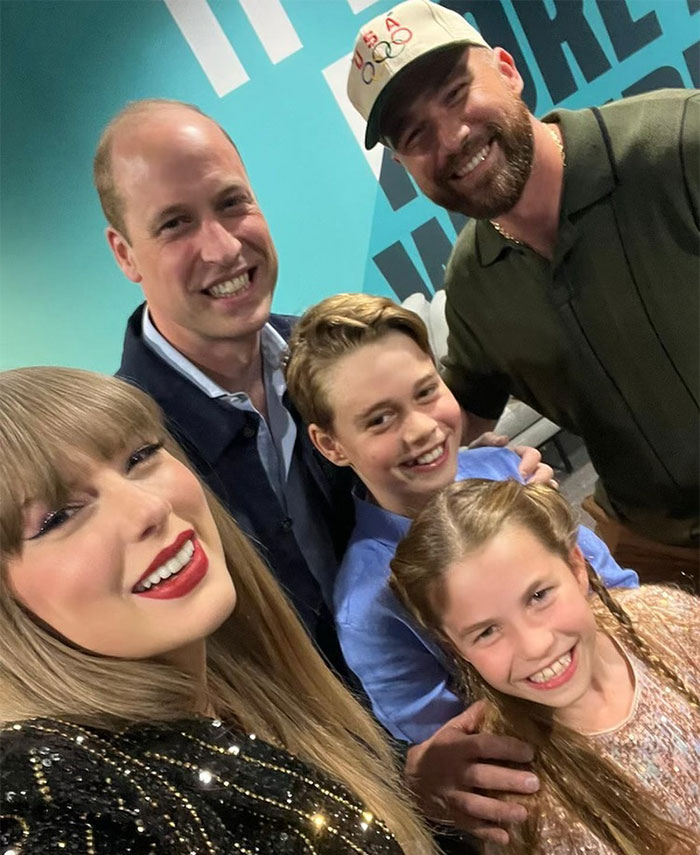 Group photo including Taylor Swift and Travis Kelce, smiling indoors with others.