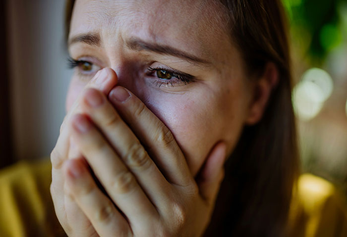 A woman looks anxious, covering her mouth with her hands, concerned about a student's comment. A woman looks anxious, covering her mouth with her hands, concerned about a student's comment.