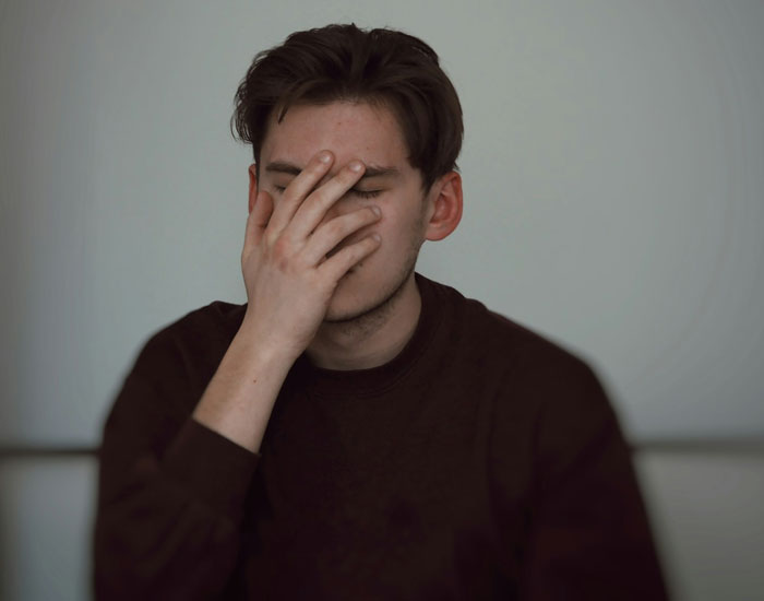 Teen covering face with hand, frustrated about someone using his expensive skincare.