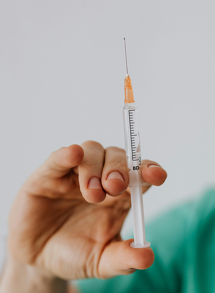 Hand holding a syringe.