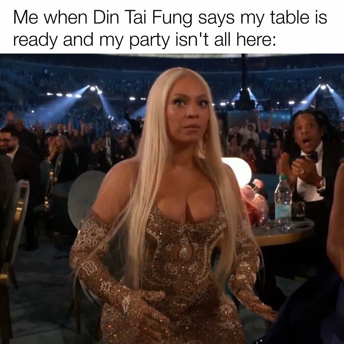 Woman in a gold dress at a crowded event, reacting humorously.