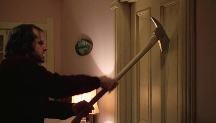 Person swinging an axe at a wooden door, evoking a memorable movie scene.