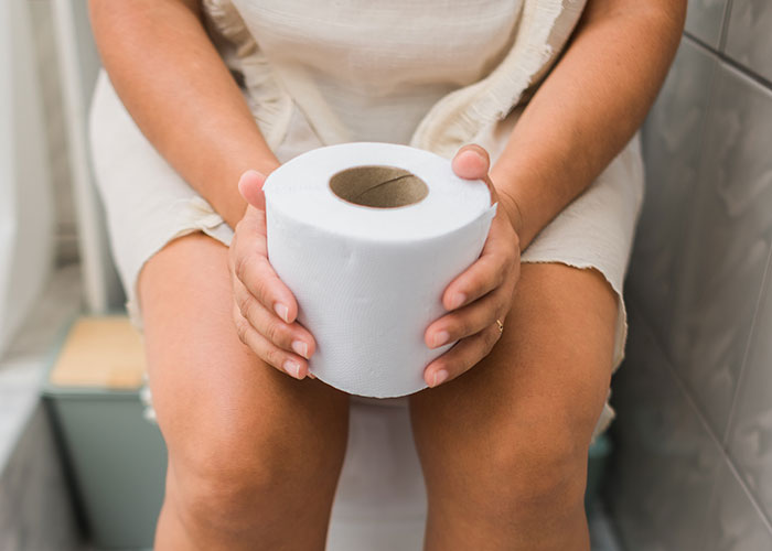 Woman holding toilet paper while sitting, exploring new aspects of relationships.