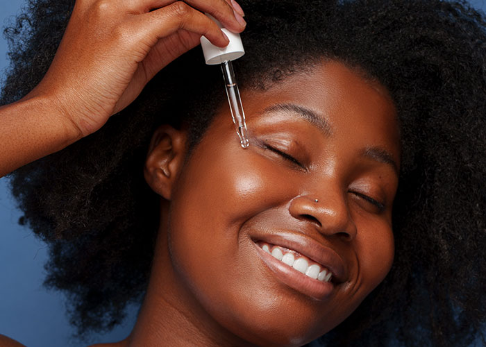 Woman applying serum with a dropper, highlighting skincare routine insights for women.