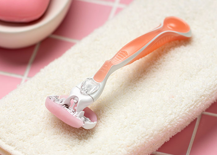 Women's razor on a towel, showcasing bathroom essentials in a setting focused on personal care and grooming.