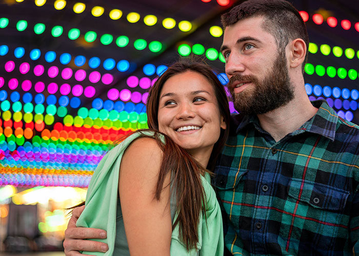 Couple smiling under colorful lights, highlighting relationship insights for men about women.