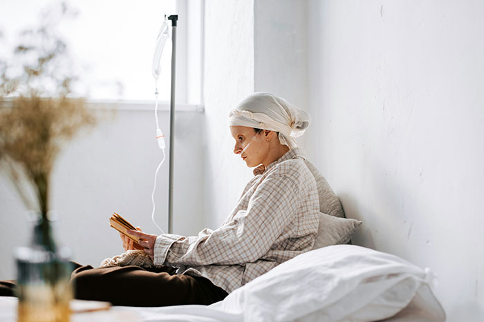 A person in a hospital bed reading a book, illustrating a moment of solitude and reflection related to grief.