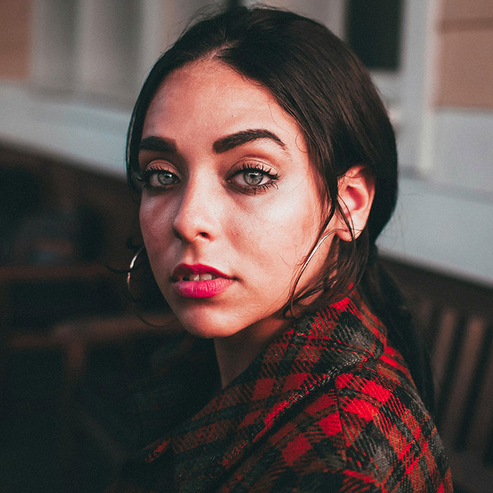 Woman in a red plaid coat, gazing thoughtfully, capturing the essence of grief and emotion.