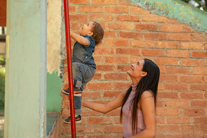 A woman helps a child climb, illustrating an experience related to understanding grief.
