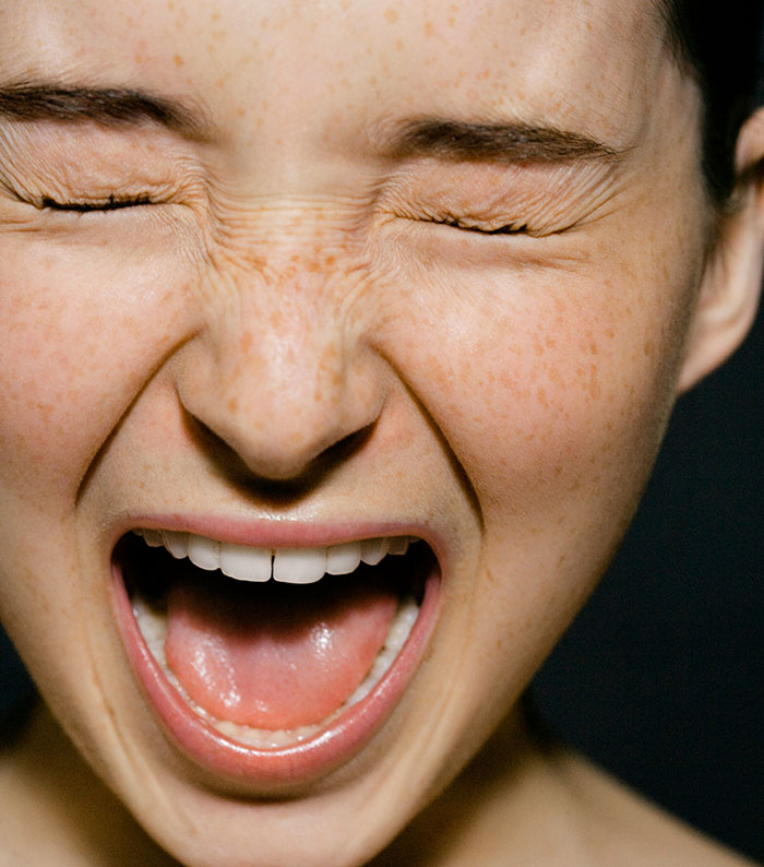 A person with closed eyes and an open mouth, expressing intense grief.