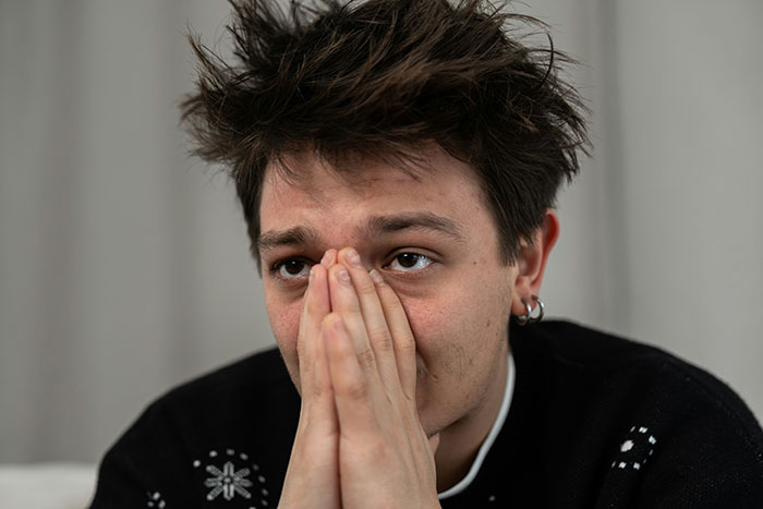 Young man with messy hair covering his face with hands, expressing worry and regret about how to ruin your entire life.