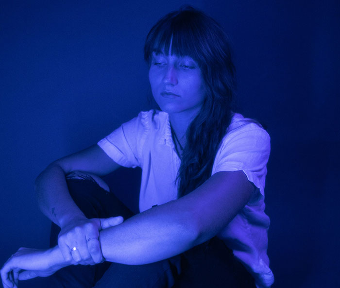 Young woman sitting alone looking sad and thoughtful, illustrating how to ruin your life through sobering personal stories.