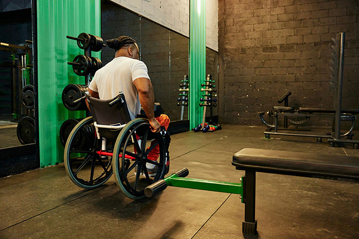 Man in a wheelchair exercising in a gym, illustrating stories on how to ruin your entire life with challenges and struggles.