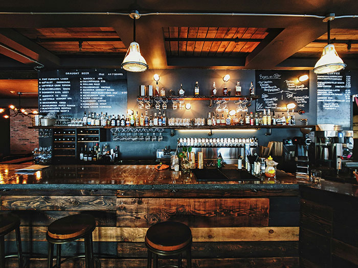 Rustic bar interior with wooden stools and shelves displaying liquor bottles, reflecting stories of how to ruin your life.