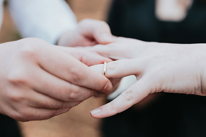 Close-up of a person placing a ring on another’s finger, representing a moment that could ruin your entire life.