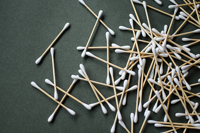 Cotton swabs scattered on a dark green surface, illustrating frugality.