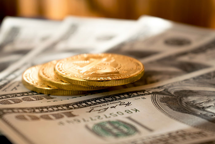Gold coins on top of dollar bills, highlighting concepts of frugality and financial choices.