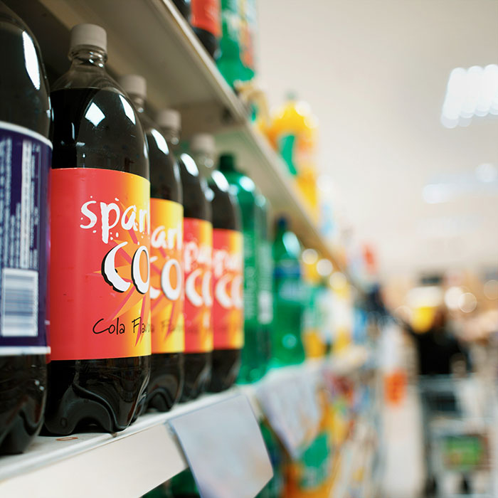 Frugality taken too far, soda bottles on a supermarket shelf, with blurred background.