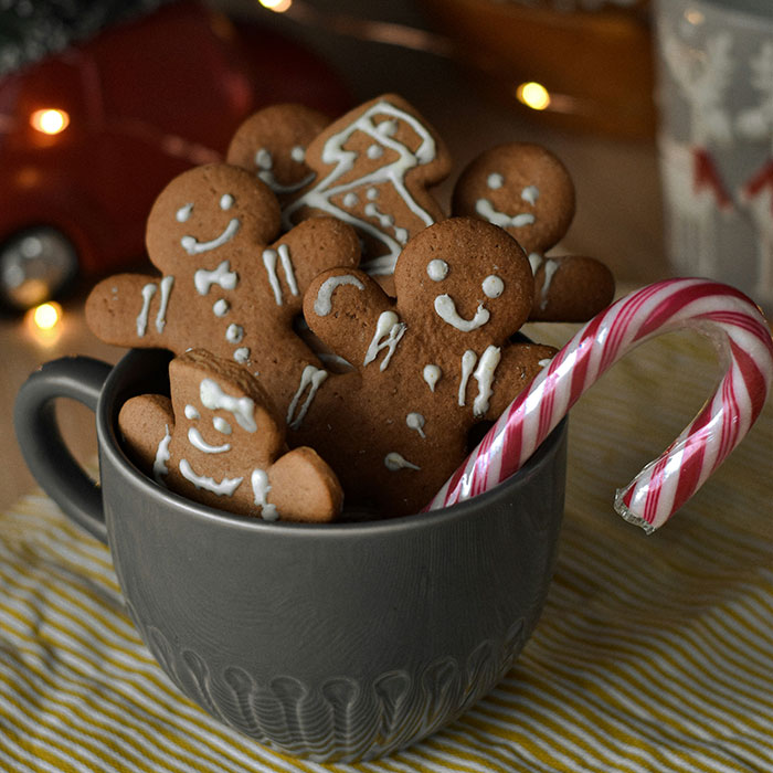 Gingerbread cookies and a candy cane in a gray mug, representing frugality in holiday treats.