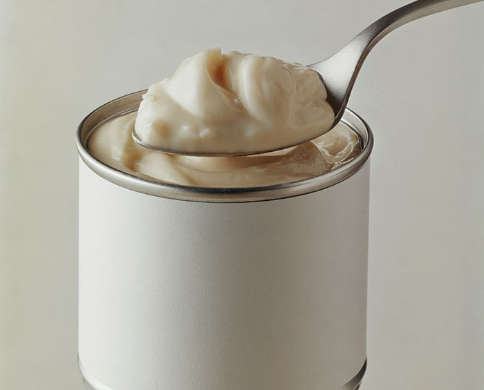 A spoon scooping creamy content from a can, symbolizing extreme frugality.