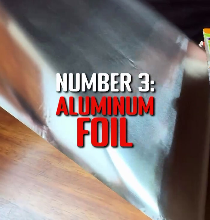 Aluminum foil labeled as a toxic kitchen item on wooden surface. Aluminum foil labeled as a toxic kitchen item on wooden surface.