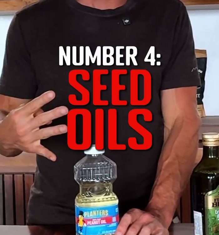 Man holding up three fingers, with text highlighting "Seed Oils" as toxic items in kitchens. Bottles on the table. Man holding up three fingers, with text highlighting "Seed Oils" as toxic items in kitchens. Bottles on the table.