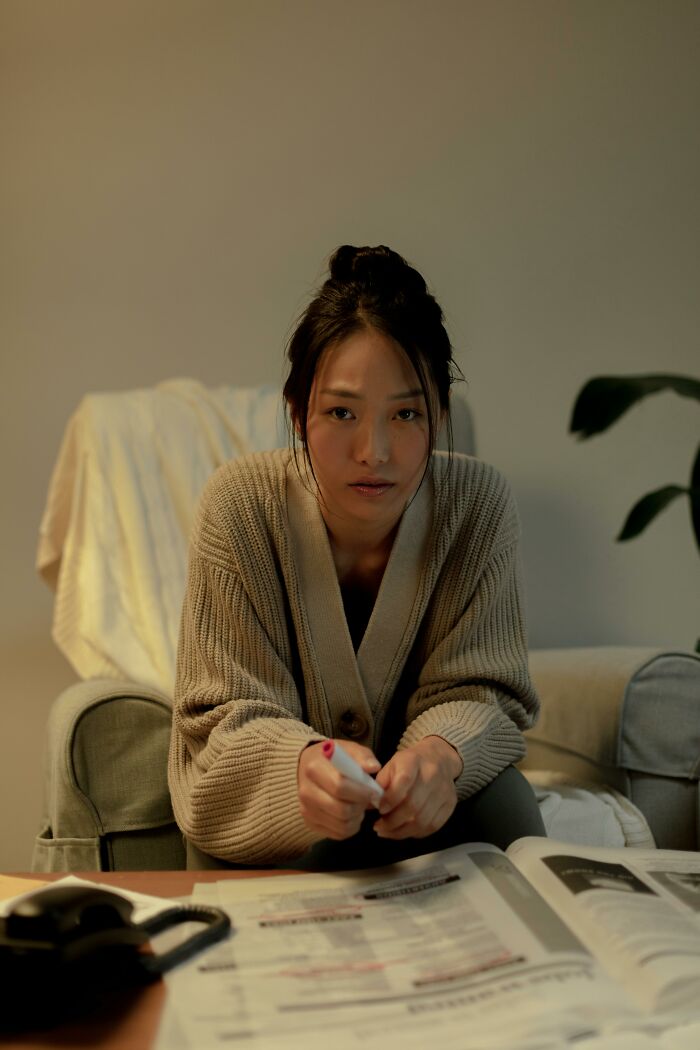 Person sitting on a couch, looking serious, with a remote in hand, highlighting a common yet overlooked traumatizing experience.