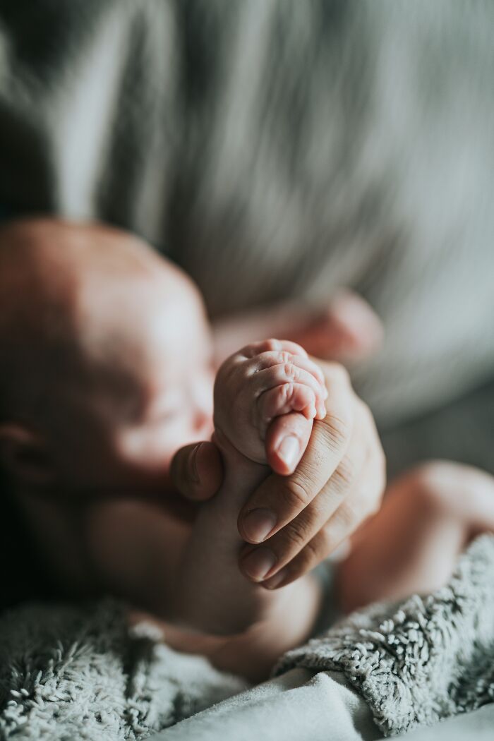 Baby gripping an adult's hand, symbolizing support during traumatizing experiences.