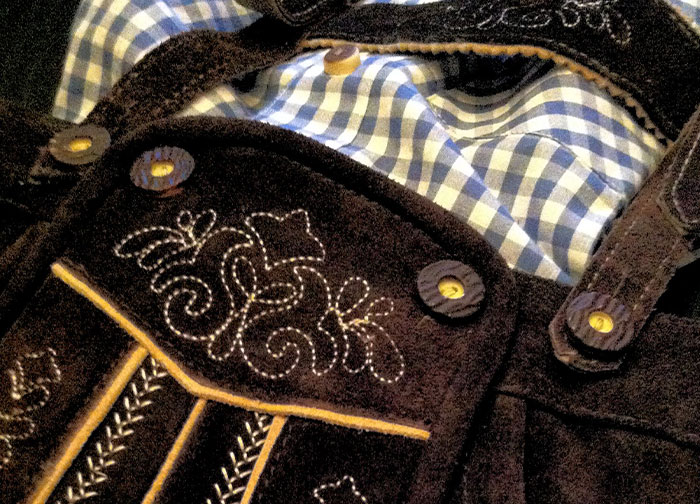 Traditional Bavarian attire with blue checkered shirt and embroidered leather details, representing homeland culture.