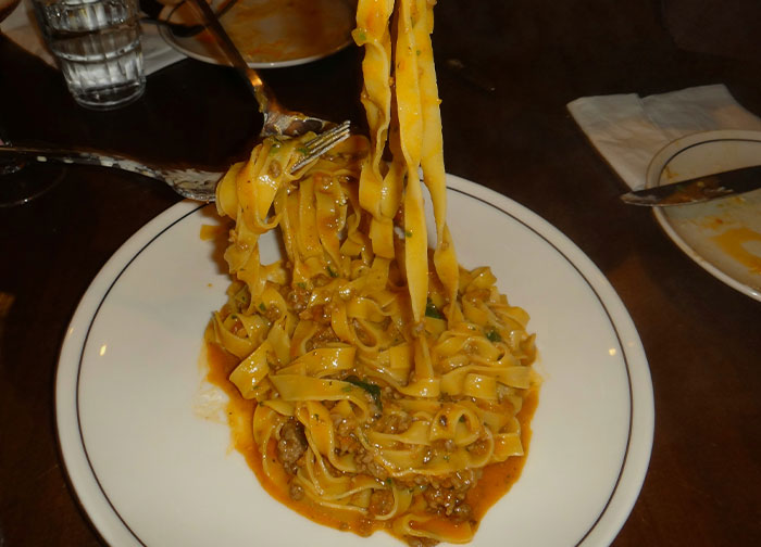 Tangled pasta with meat sauce being lifted, on a plate, relating to wild questions about homeland.