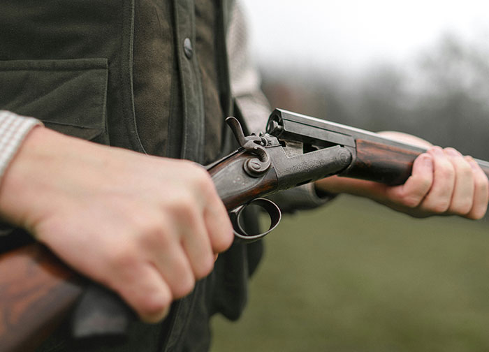 Person holding a s*****n outdoors, demonstrating hunting techniques, connected to questions about their homeland's culture.