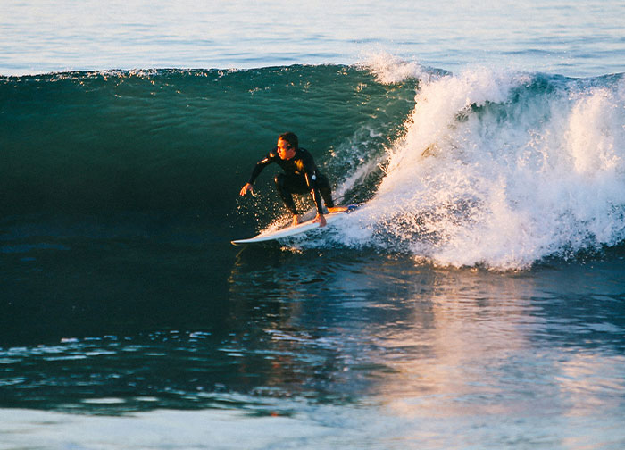 Surfer riding a wave at sunset, showcasing skill and adventure.