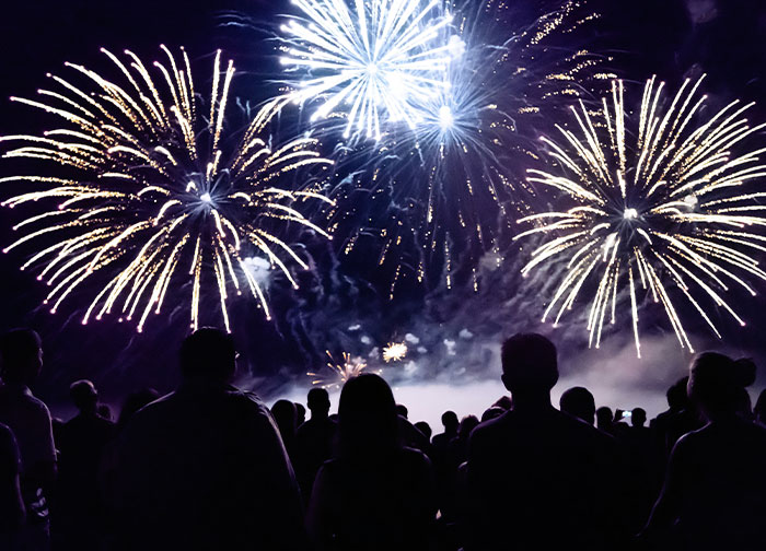 People watching vibrant fireworks in the night sky, celebrating their homeland with colorful explosions.