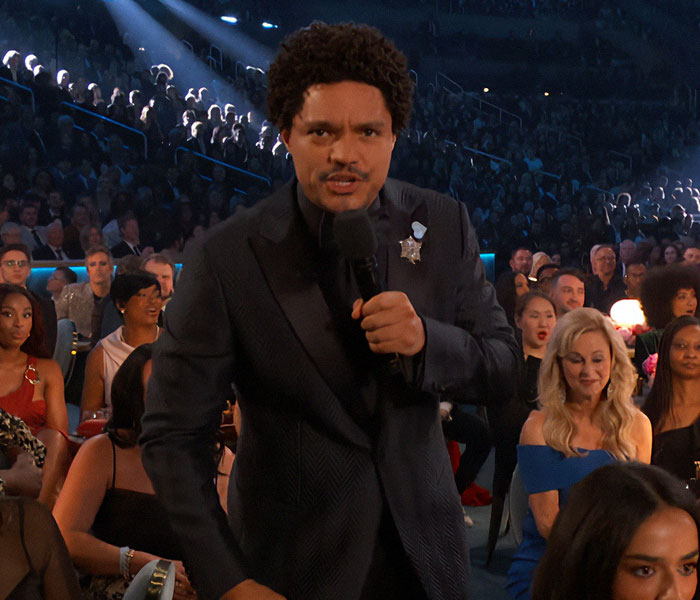 A host with a microphone at the 2025 Grammy Awards, engaging with the audience during a moment on stage.