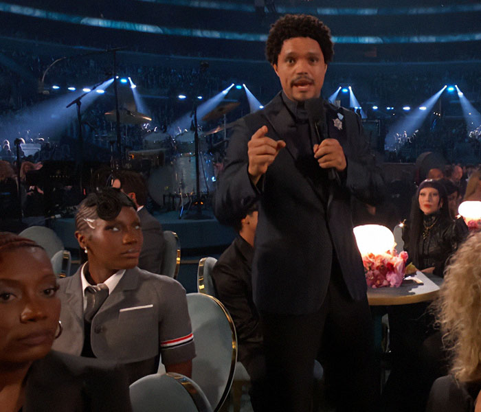Man in a suit speaking to the camera at the 2025 Grammy Awards, surrounded by seated guests in formal attire.