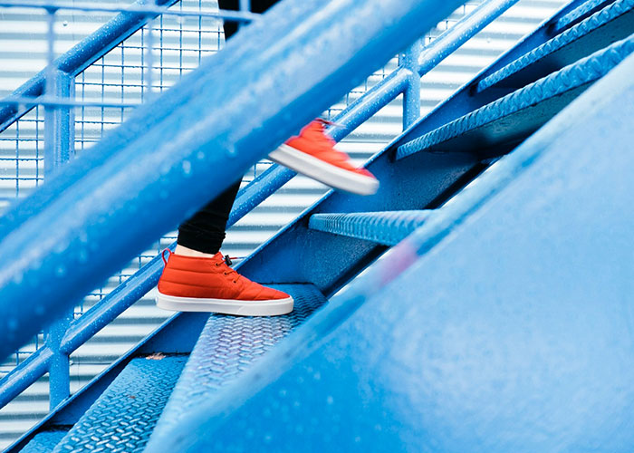 Person wearing red sneakers ascending blue stairs, symbolizing steps towards 10K daily.