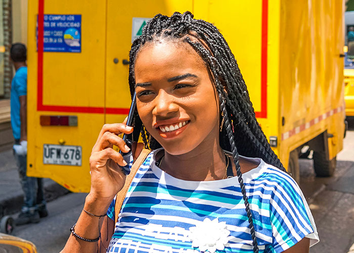 Woman smiling while talking on phone, walking outdoors, suggesting tips to get 10K steps daily.