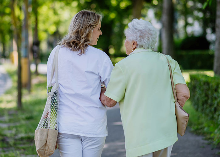 Two women walking outdoors on a path, engaging in conversation to achieve 10K steps a day.